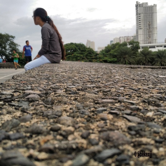 A Girl sitting on a stony pavement